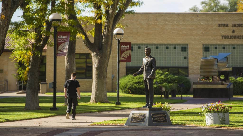 student walking past Hoag statue in Pueblo campus courtyard